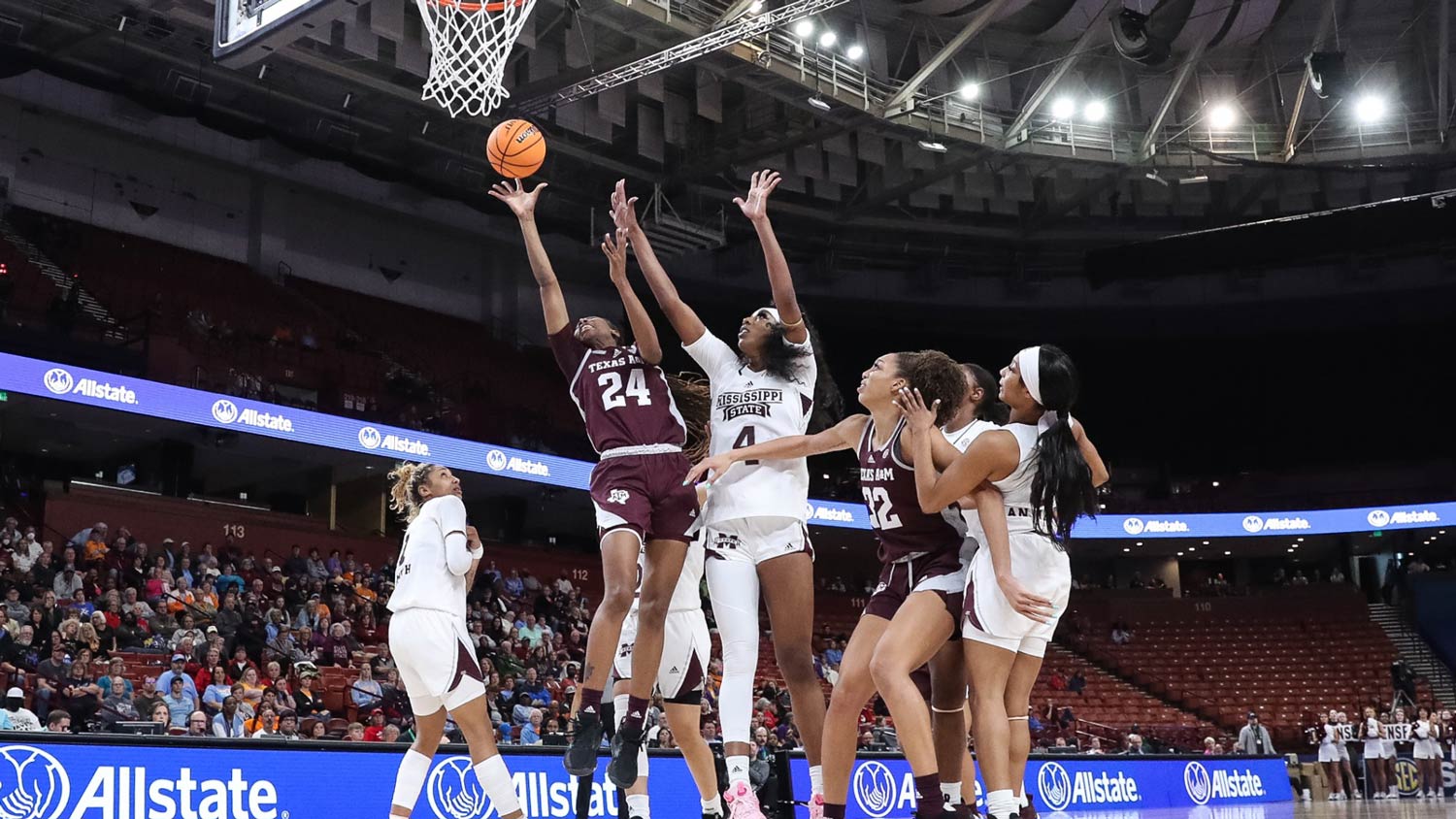 A Texas A&M basketball player shoots over defensive players the ball in the paint